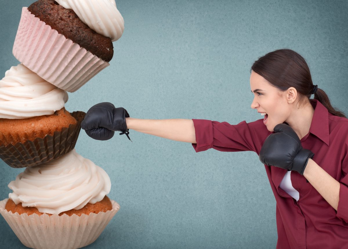 young woman punching giant cupcakes
