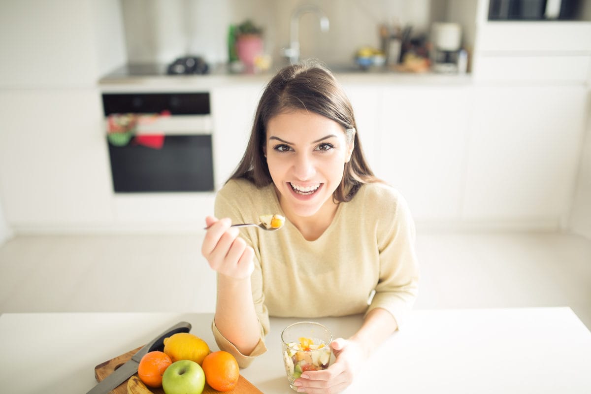Healthy looking cheerful woman eating homemade organic fruit mix