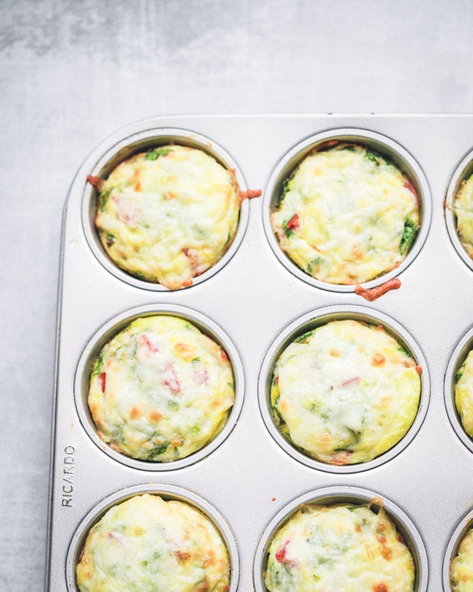 Healthy Breakfast Egg Muffins in a muffin pan, topped with mozzarella cheese on top. Baked.