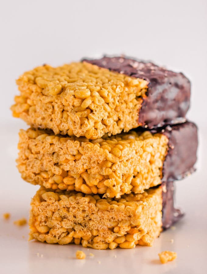 These healthy & no-bake vegan rice crispy treats are made with only 3 ingredients: peanut butter, maple syrup, and crispy rice cereal. No marshmallow here. Protein powder and chocolate topping are optional. This easy, clean eating snack can be whipped together in less than 10 minutes and is TOTALLY kid approved! :) | onecleverchef.com #glutenfree #dairyfree #veganprotein #proteinsnack #family #fun