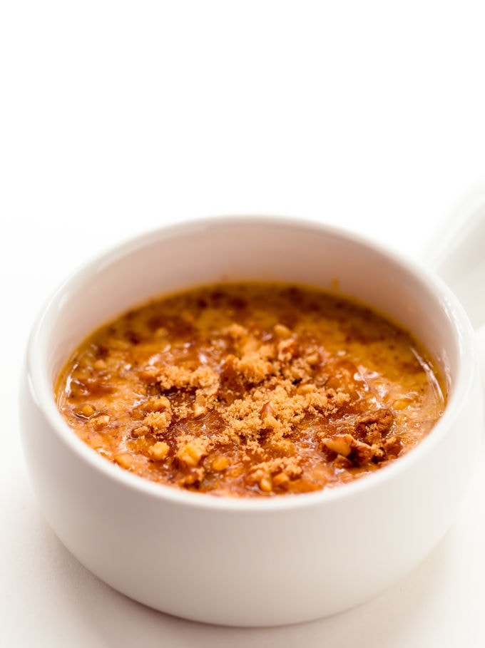 Banana cake batter in a mug topped with chopped walnuts and coconut sugar.
