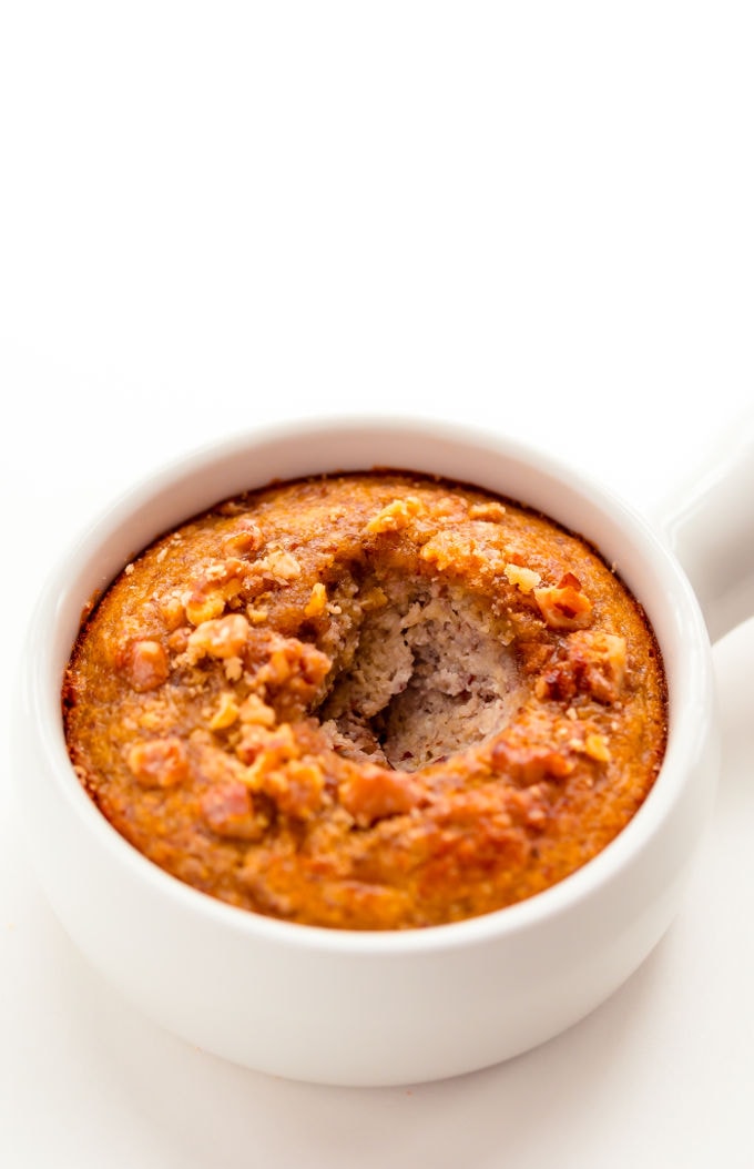 Banana nut cake in a mug with a large bite missing on top.