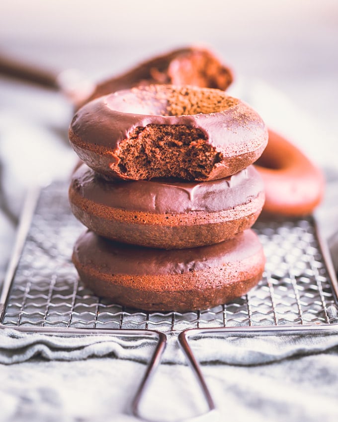 3 chocolate protein donuts stacked on a cooling rack.