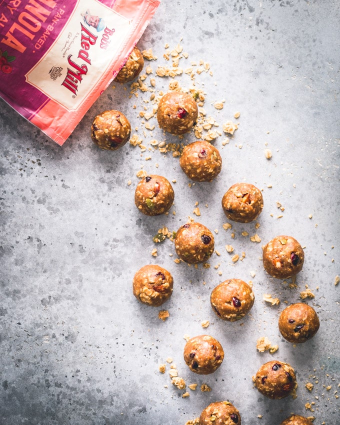 Cranberry Almond Granola Protein Balls on a blue background with a bobs red mill pan-baked granola bag